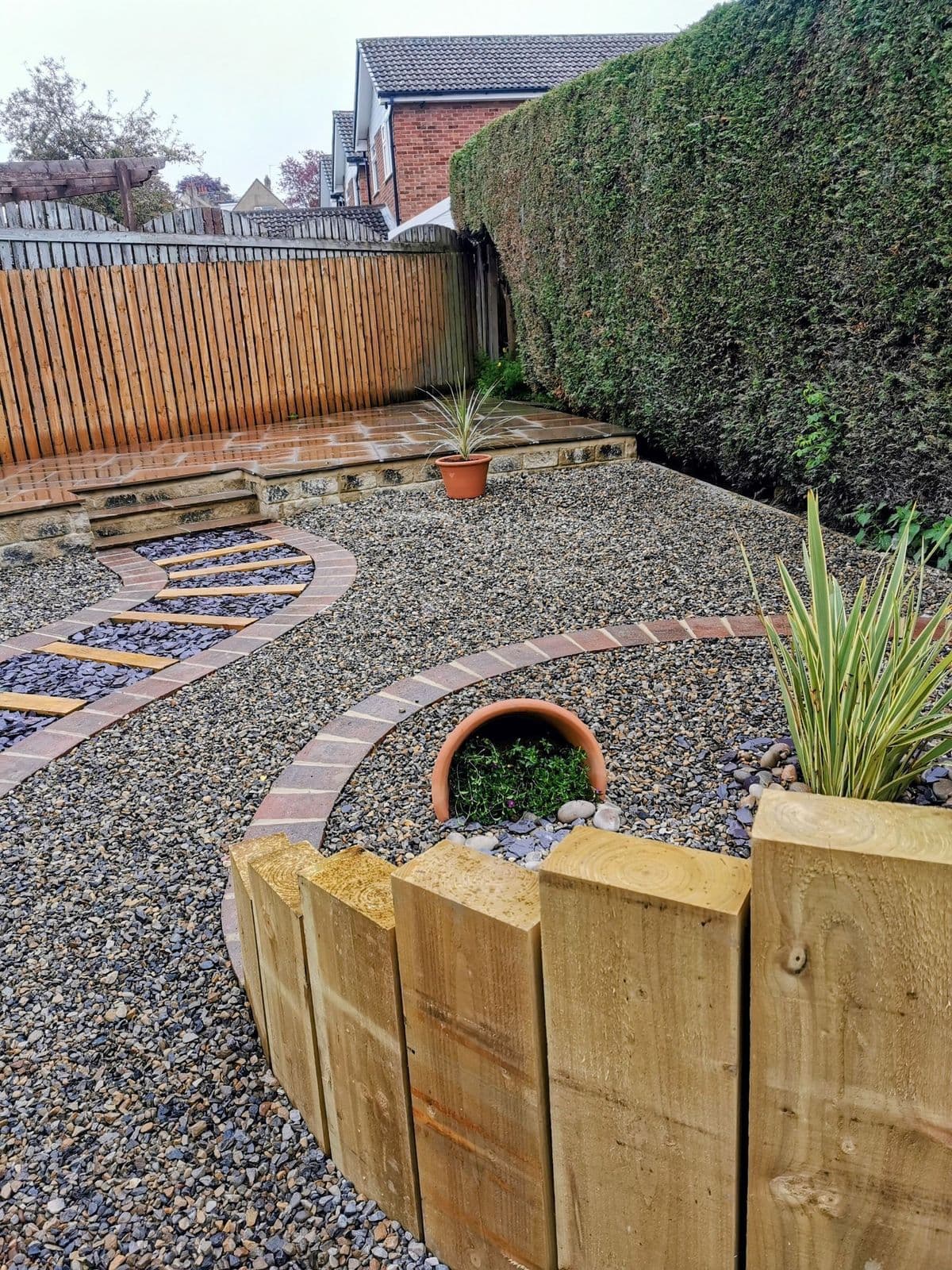 The finished garden: a slate and gravel path curving past a raised sleeper planter